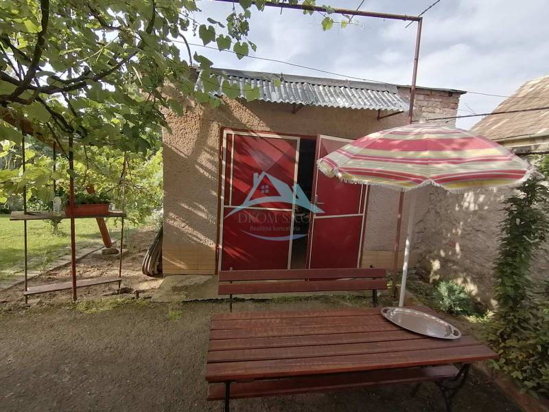 Családi ház kertje Hrkovce-ben asztallal és napernyővel.