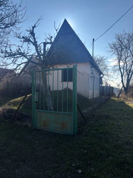 Kis házikó fákkal körülvéve, bekerített kert, ideális üdülőteleknek.