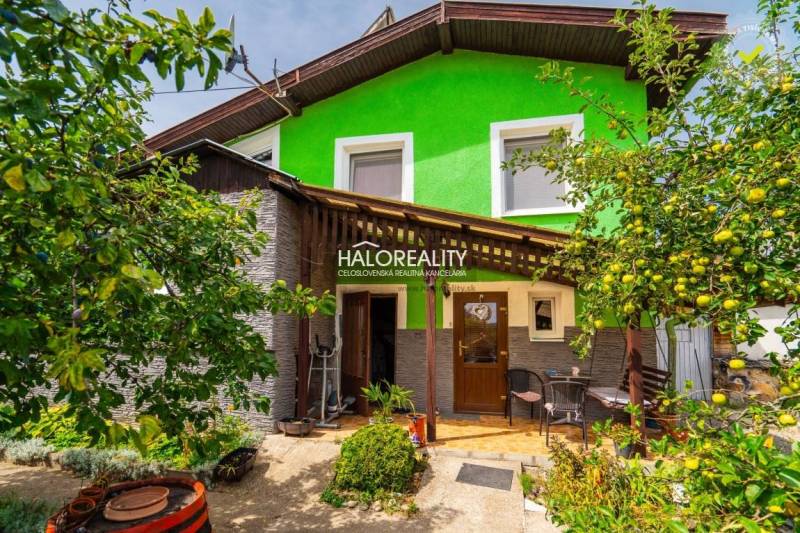 Családi ház Selmecbányán fa verandával, zölddel és gyümölcsfákkal körülvéve.