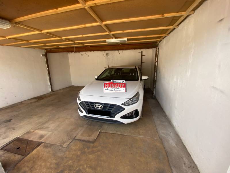 A garázs belseje egy fehér Hyundai márkájú autóval, amely bent van leparkolva.