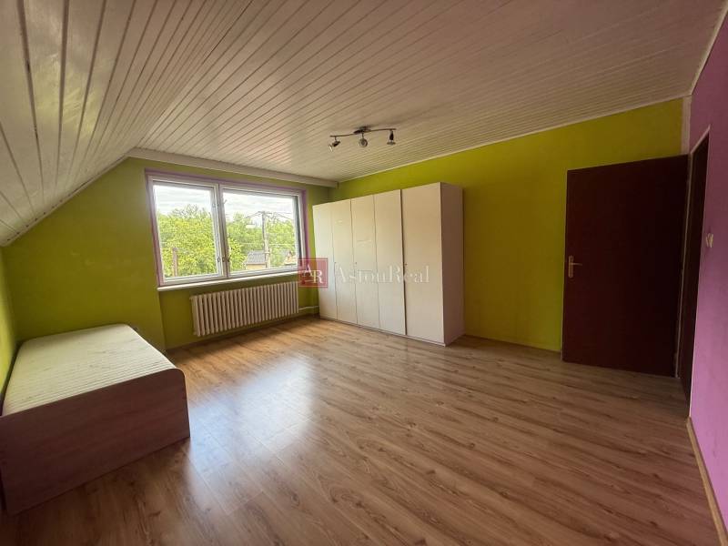 Szoba egy családi házban laminált padlóval, színes falakkal, ággyal és szekrénnyel.