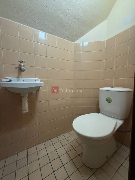 WC mosdókagylóval egy családi házban, bézs csempével burkolva.