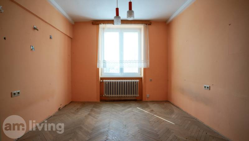 Üres szoba egy kétszobás lakásban narancssárga falakkal és fa padlóval.