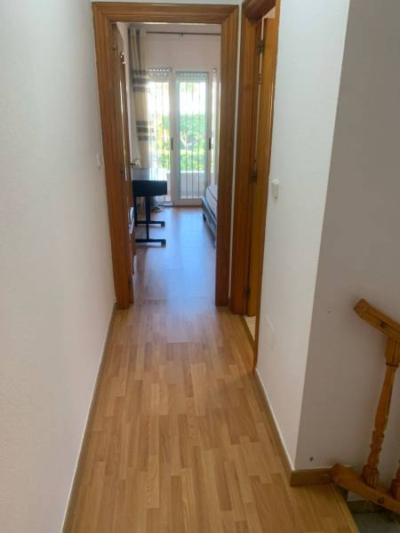 A családi ház folyosója egy szobába vezet, ahol van egy ágy és egy íróasztal.