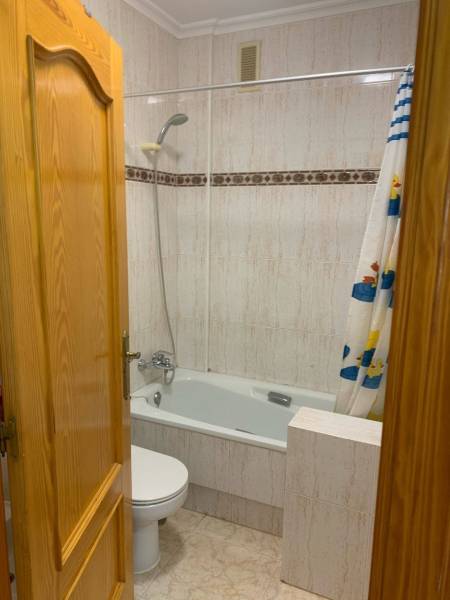 Fürdőszoba családi házban káddal, WC-vel és kacsás zuhanyfüggönnyel.