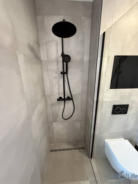 Zuhanykabin és WC fekete kiegészítőkkel egy kétszobás lakásban.