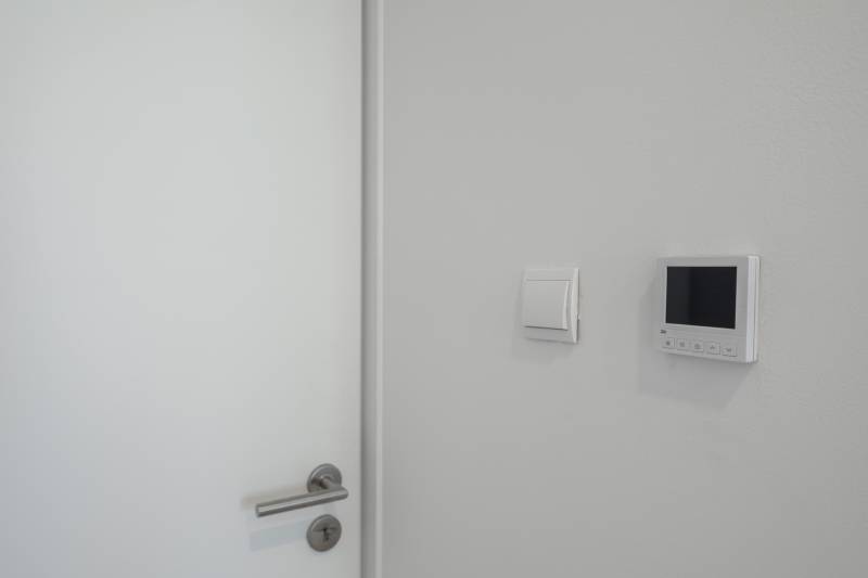 Ajtó fém kilinccsel, kapcsolóval és vezérlőpanellel a családi házban.