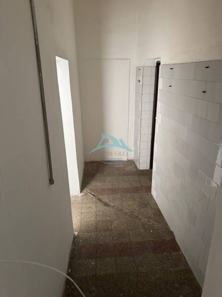 Keskeny belső tér csempével és burkolt fallal üzlethelyiségben.