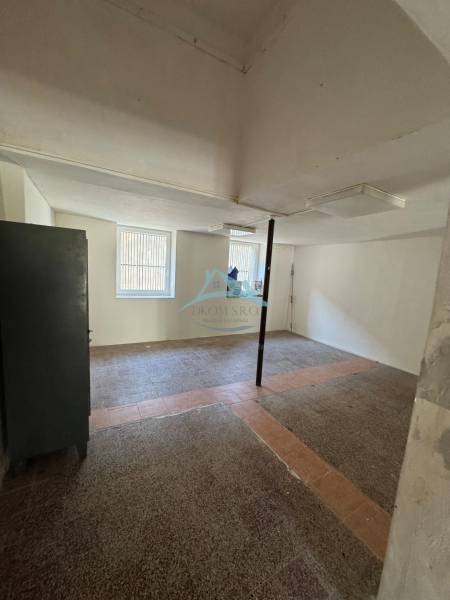 Üzlethelyiség szabad térrel, ablakokkal és oszloppal a szoba közepén.