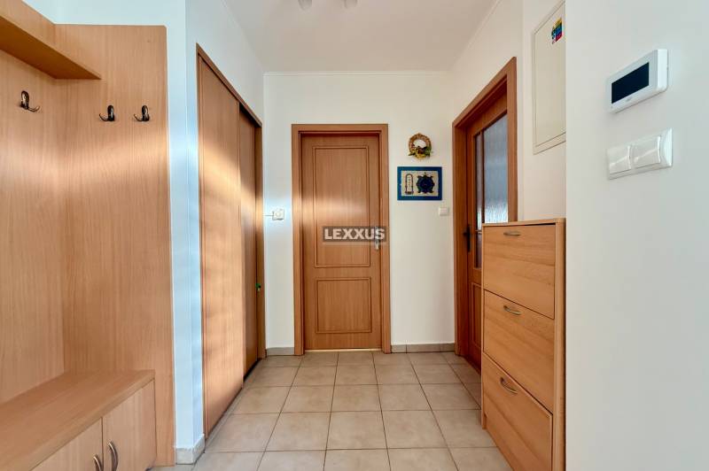 Folyosó egy családi házban fa bútorokkal és csempével a padlón.