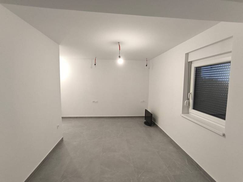 Üres szoba egy négy szobás lakásban fehér falakkal és szürke padlóval.