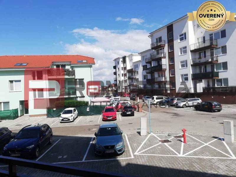 Parkoló a Slavomírova utcán, autókkal az épületek előtt városi környezetben.