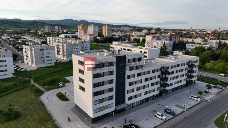 Kereskedelmi helyiségek a pezinki Obchodná utcában, lakóházakkal és zöldterületekkel körülvéve.