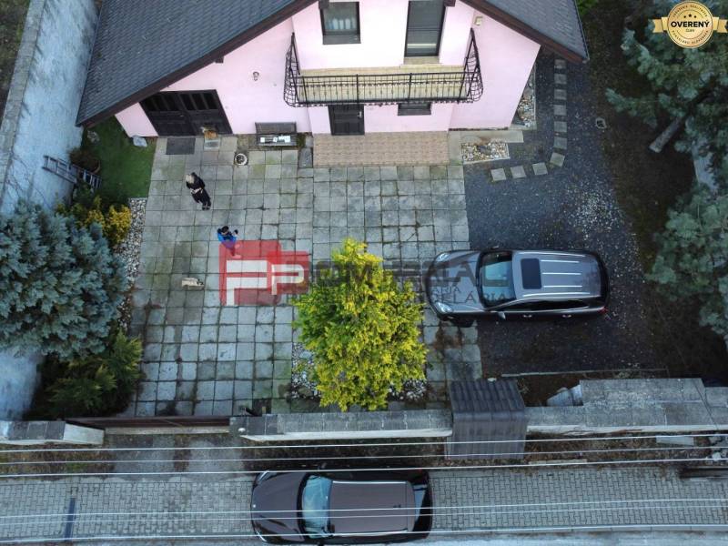 Családi ház Pílán tágas udvarral, parkoló autókkal és gondozott kerttel.