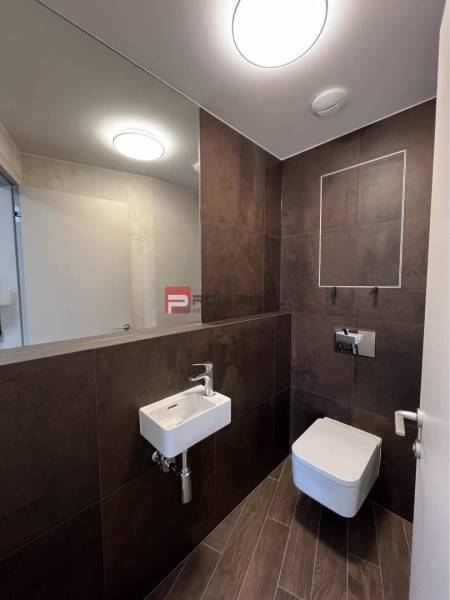 Fürdőszobai üzlethelyiség mosdóval, tükörrel és WC-vel.