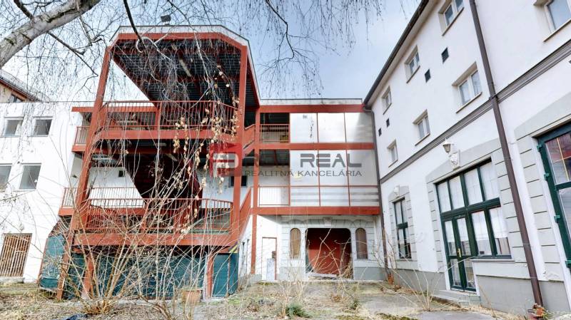 Az Ľ. Podjavorinská utcában található épület Trnavában külső fém lépcsővel és üvegezett ablakokkal.