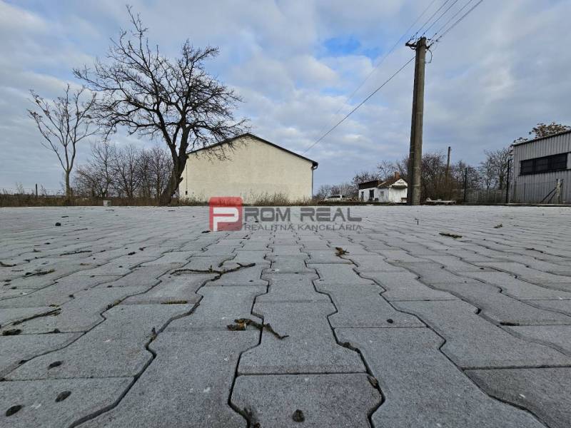 Járda a Partizánska utcán, raktárak és csarnokok mellett, csupasz fákkal.