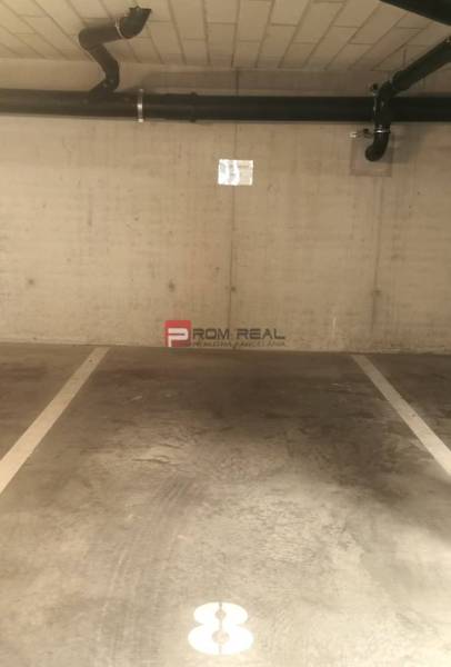 Parkolóhely a garázsban, csövekkel a falon.