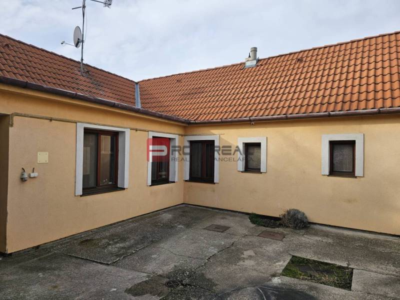A Pezinkben, a Nap utcában található családi ház udvara betonburkolattal és narancssárga homlokzattal.