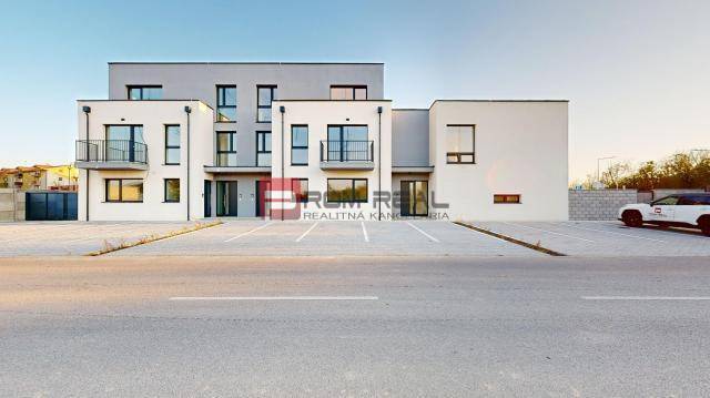 Épület a Bottova utcán, modern építészet, parkoló és családi ház a háttérben.