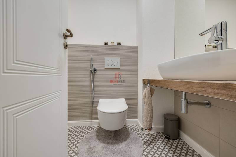Fürdőszoba függesztett WC-vel és mosdóval egy háromszobás lakásban geometrikus csempével.