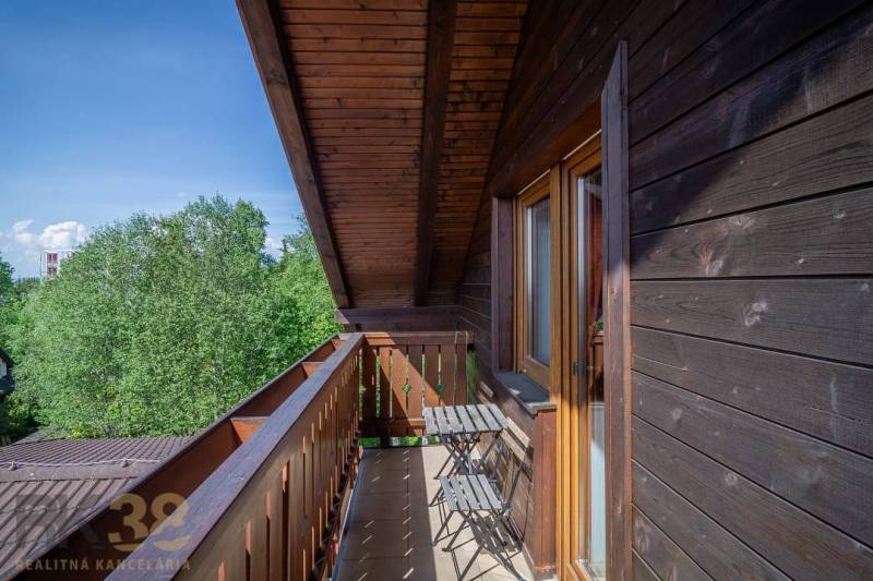 Erkély asztallal és székekkel egy pihenő apartmanban, kilátással a fákra a Magas-Tátrában.