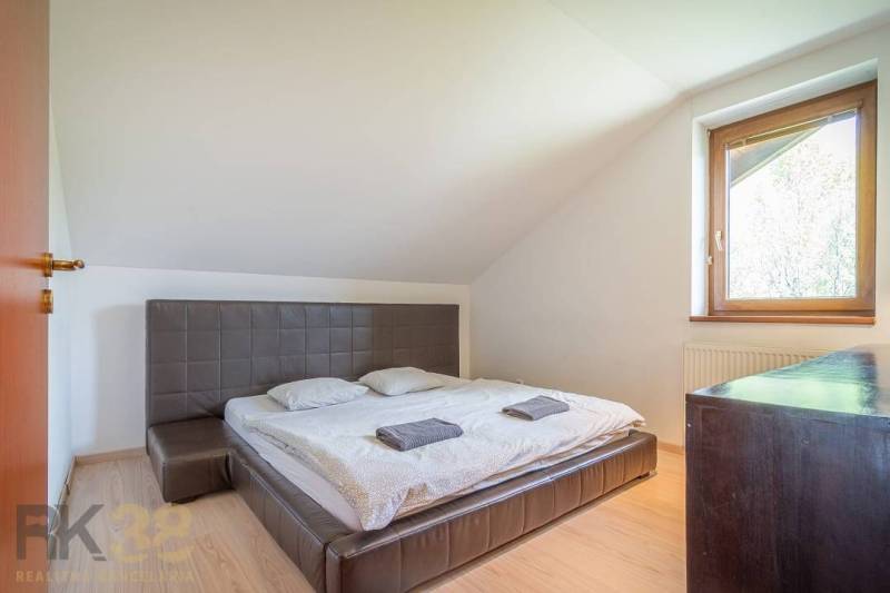 Hálószoba a nyaraló apartmanban kétágyas szobával, ablakkal, fa bútorokkal és tetőlejtésekkel.