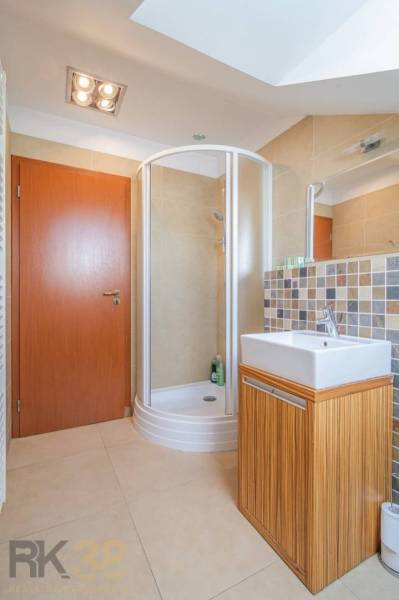 Fürdőszoba a nyaraló apartmanban zuhanyzóval és négyzet alakú mosdóval.