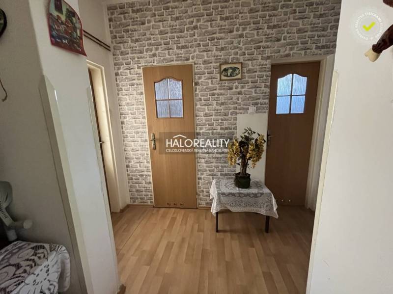 Folyosó egy háromszobás lakásban téglamintás fallal és faajtókkal.