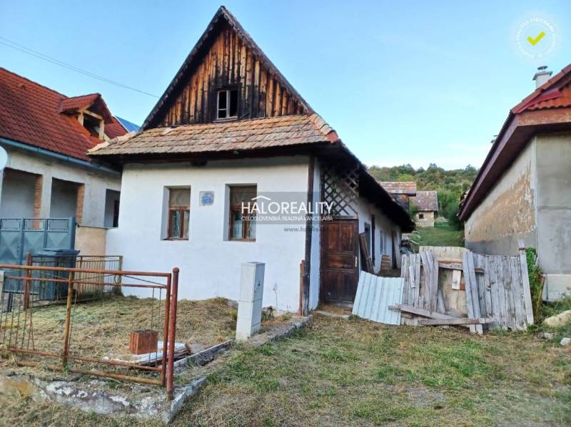Családi ház Ladzanyban ferde tetővel és kerttel, más épületek által körülvéve.