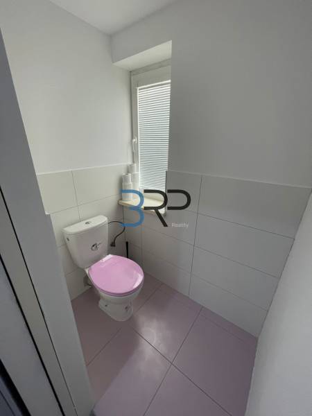 Fürdőszoba egy kétszobás lakásban rózsaszín WC-vel és fehér csempével.