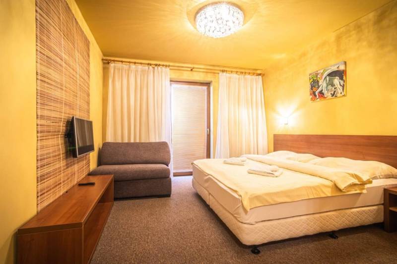 Hálószoba nyaraló apartmanban franciaággyal, kanapéval és televízióval.