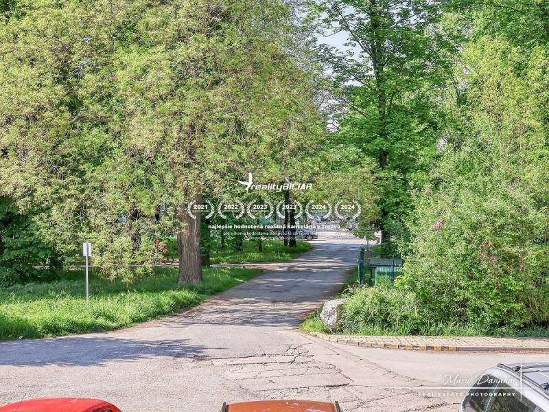 A Staničná utca Nagyszombatban fákkal szegélyezett, nyugodt városi jelenetet ábrázol.