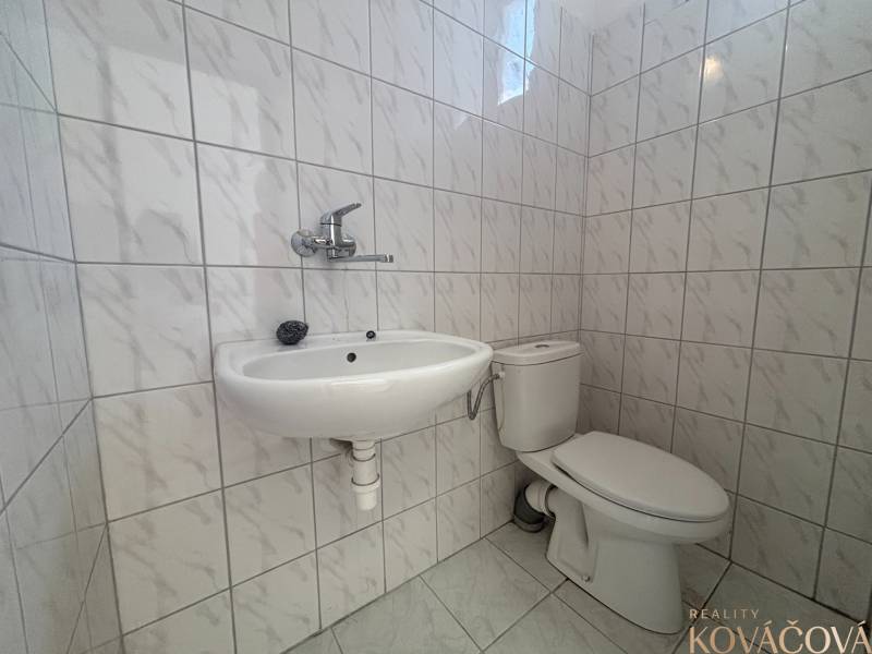 Fürdőszobai helyiségek fehér csempékkel, mosdóval és WC-vel a raktárakban és csarnokokban.