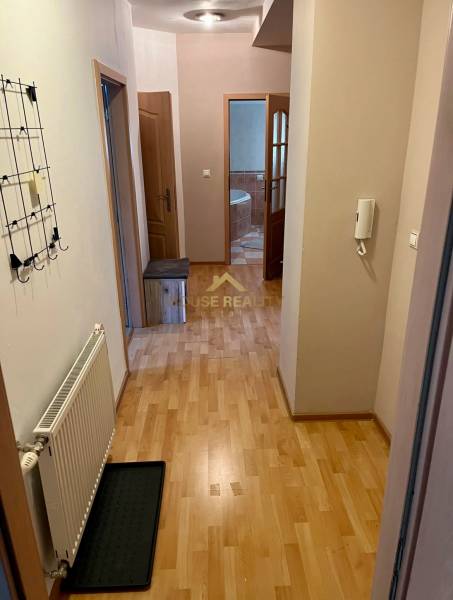 Folyosó egy kétszobás lakásban, fa padlóval, fogassal, fürdőszobába nyíló bejárattal.