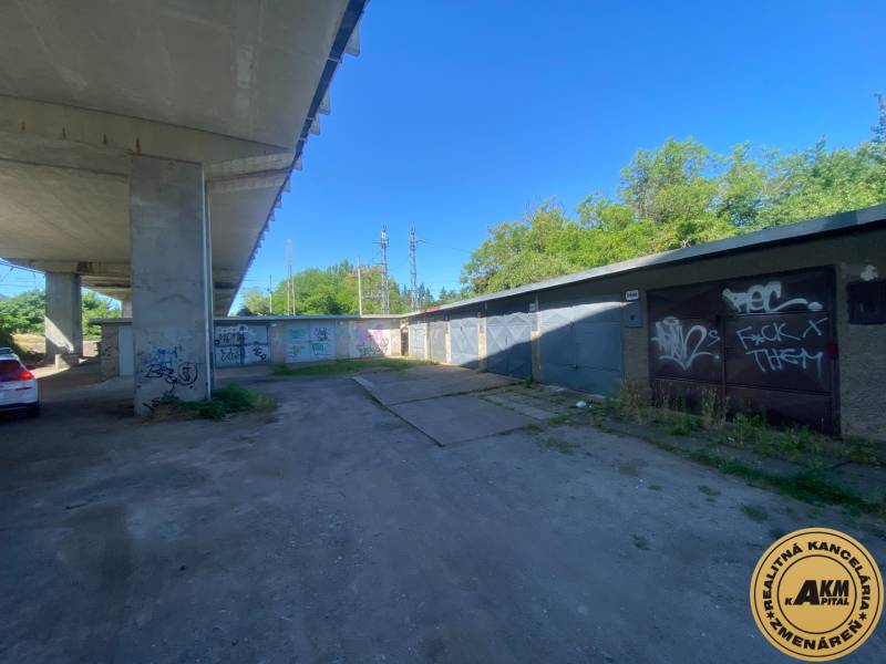 Garázsok Zólyomban a híd alatt, graffitikkel a falakon és parkoló autóval.