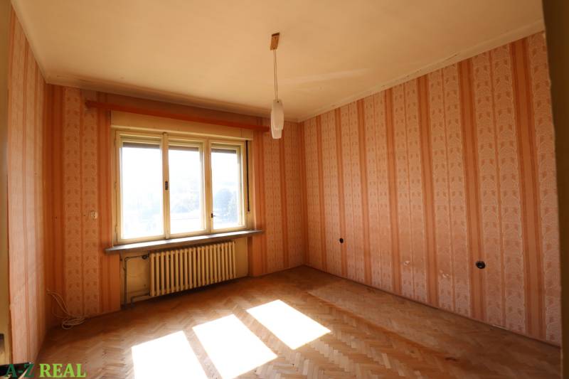 Egy családi ház szobája parkettával és ablakkal narancssárga tapétával van borítva.
