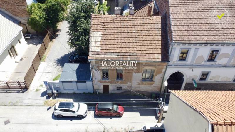 Családi ház Rimaszombatban régi homlokzattal és az utcán parkoló autókkal.
