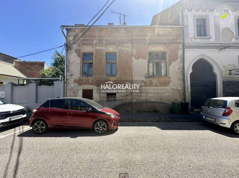 Utca Rimaszombatban történelmi családi házzal és parkoló autókkal.