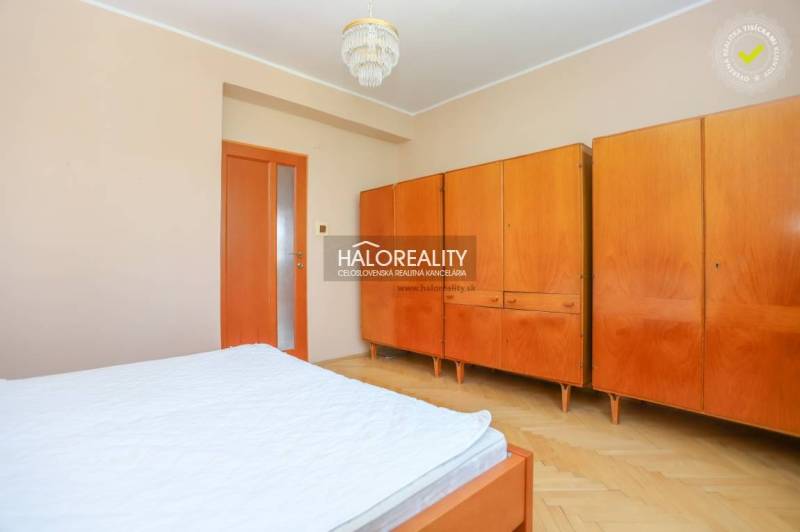Hálószoba egy háromszobás lakásban beépített szekrénnyel és fa bútorokkal.