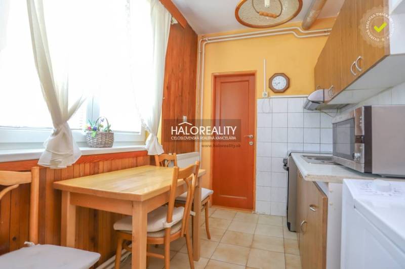 Konyha egy háromszobás lakásban faasztallal és székekkel.
