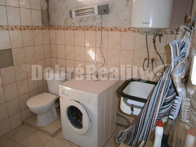 Fürdőszoba a családi házban mosógéppel, WC-vel és mosdóval.