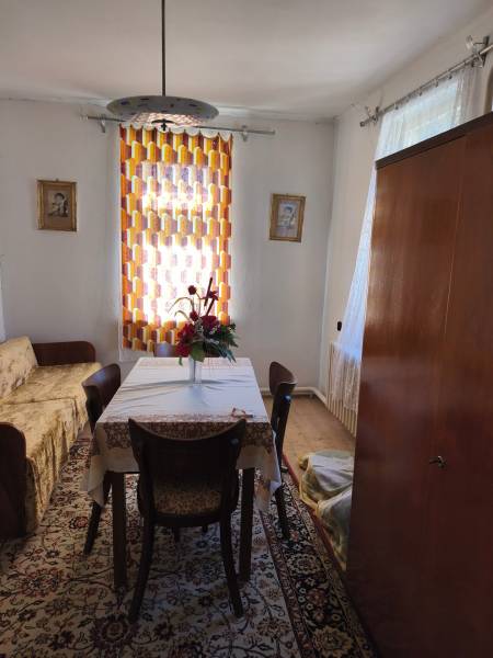 Ebédlő egy családi házban, asztallal, székekkel, virágokkal, szőnyeggel és függönnyel.