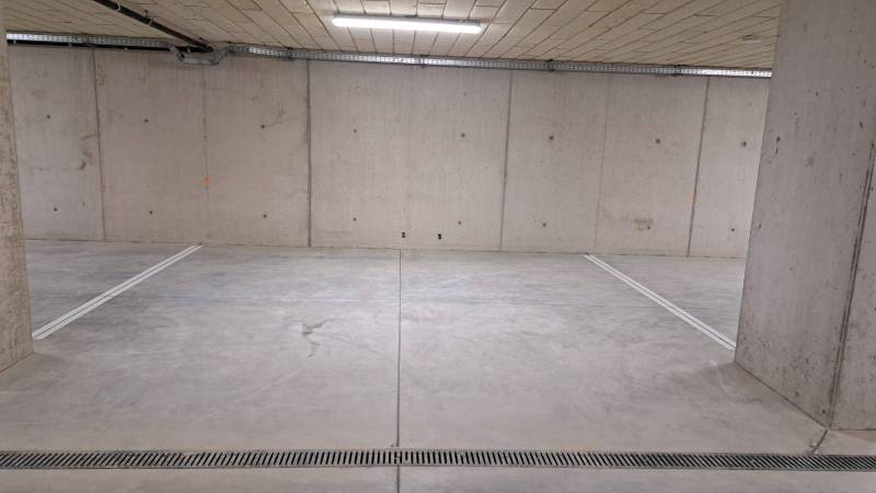 Parkolóhely egy föld alatti garázsban betonfalakkal és padlóval.
