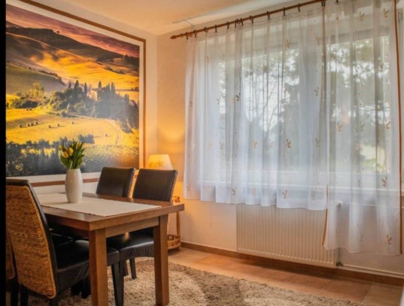 Nappali egy egyszobás lakásban, faasztallal és képes dekorációval a falon.