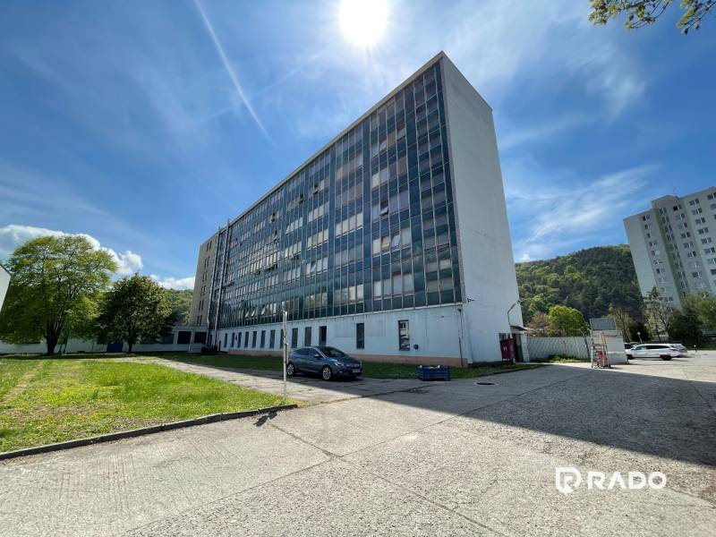 Irodák a K výstavisku utcában, Trencsénben, mellette gyep és parkoló autó.