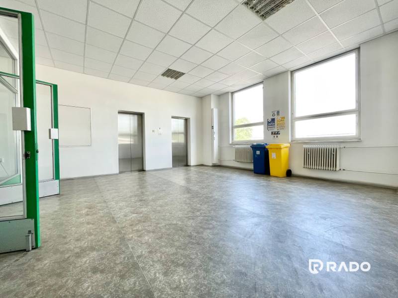 Irodák liftekkel, újrahasznosító kukákkal és radiátorokkal, világos tér.