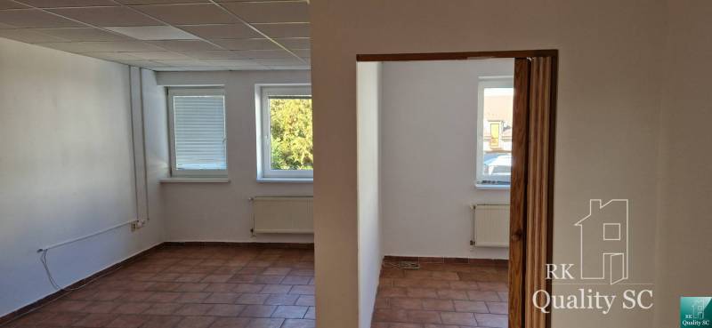 Az épület belső tere fehér falakkal, barna csempével és három ablakkal, kilátással.