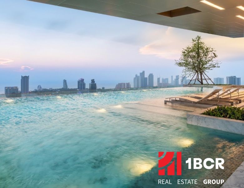 Medence napozóágyakkal és kilátással Pattaya város panorámájára, lakásépítések.