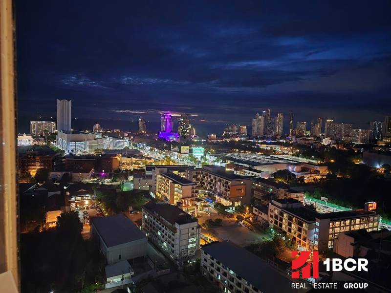 Éjszakai kilátás Pattaya városára, megvilágított épületekkel és sziluettekkel a horizonton.